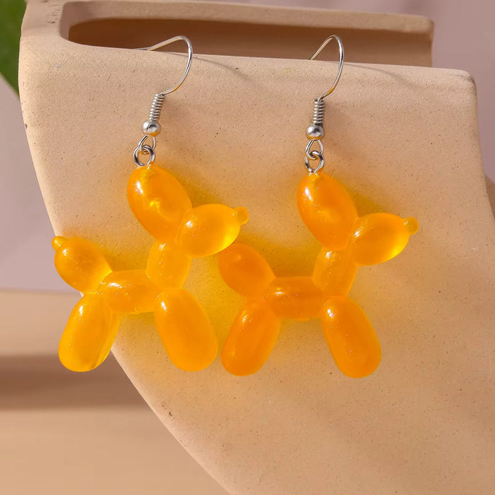 light orange balloon dog-shaped earrings on a beige surface