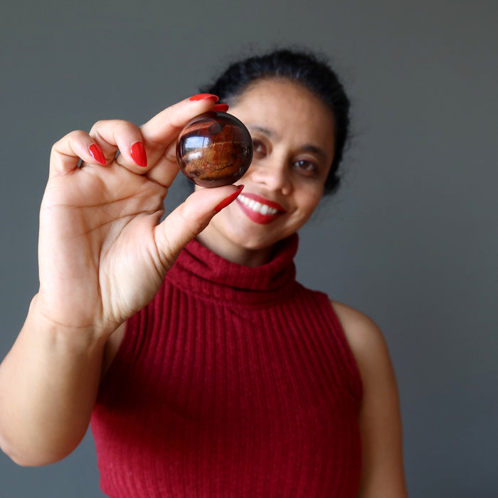 woman holding red tigers eye sphere
