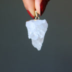 hand holding raw quartz cluster pendant in gold electroplating