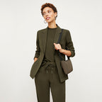 Front image of a woman standing wearing the Delaney Jogger—OrigamiTech in Olive
