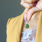 hand holding jade pendant to chest