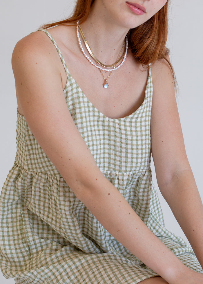 Person wearing a green checkered dress with visible jewelry on a plain background