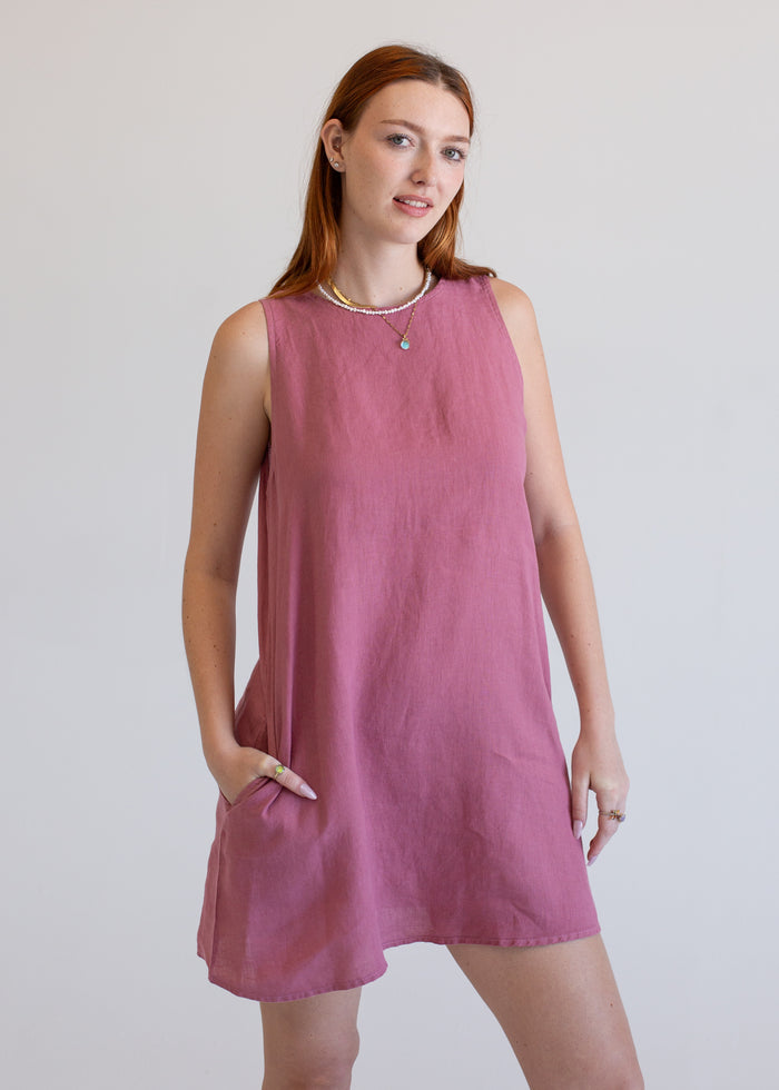 Woman wearing a pink sleeveless dress against a plain background