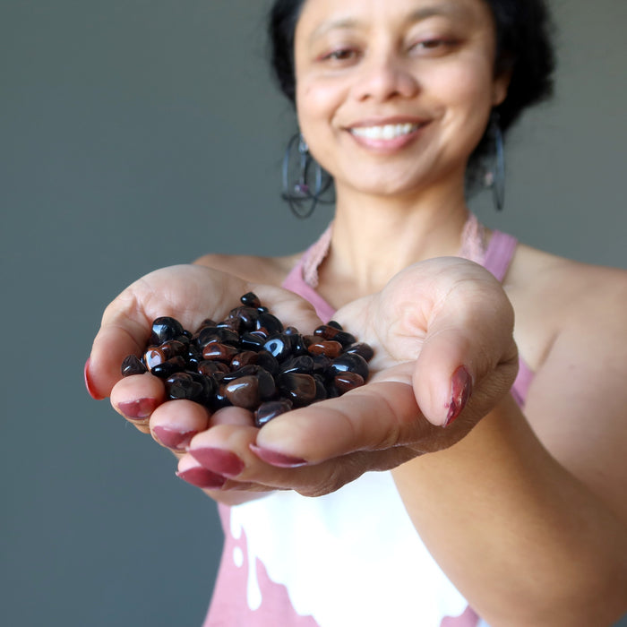 woman holding mahogany obsidian tumbled stones